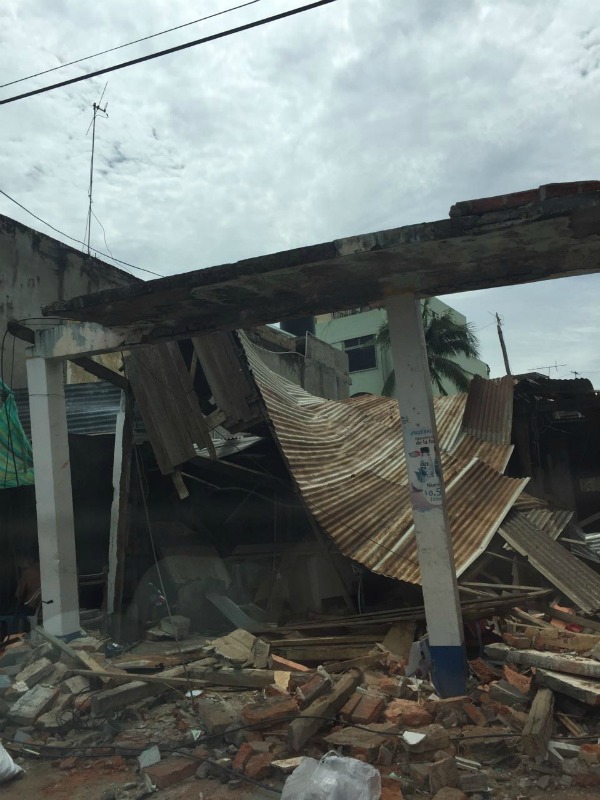 A tin collapsed and bent tin roof and tilted building supports lean atop brick rubble in the aftermath of the earthquakes in Manta, Ecuador in April 2016. 